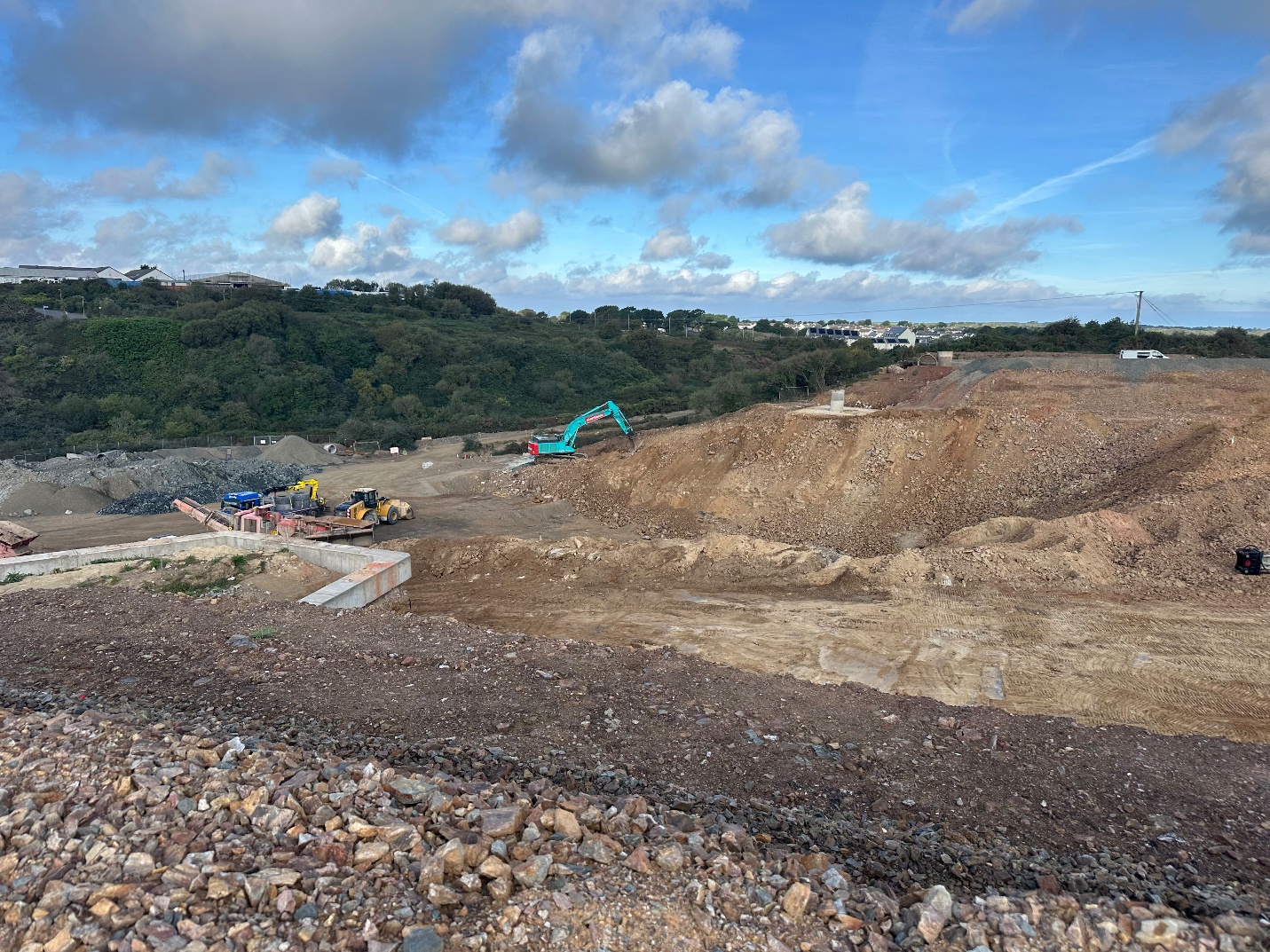 The image depicts a construction site with a partially completed structure, surrounded by a rocky terrain and a clear blue sky.

AI-generated content may be incorrect.